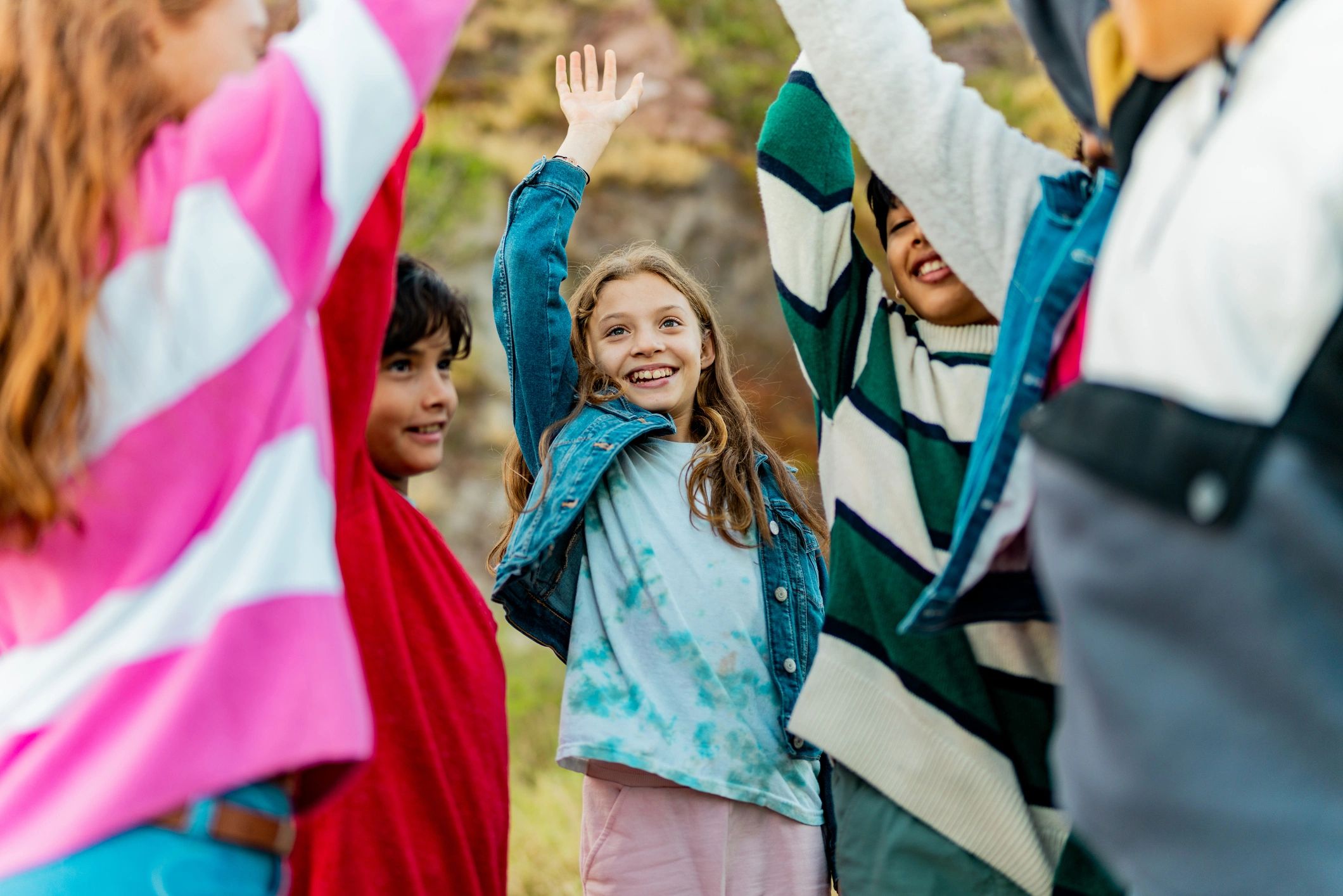 Group of kids celebrating outdoors with arms raised